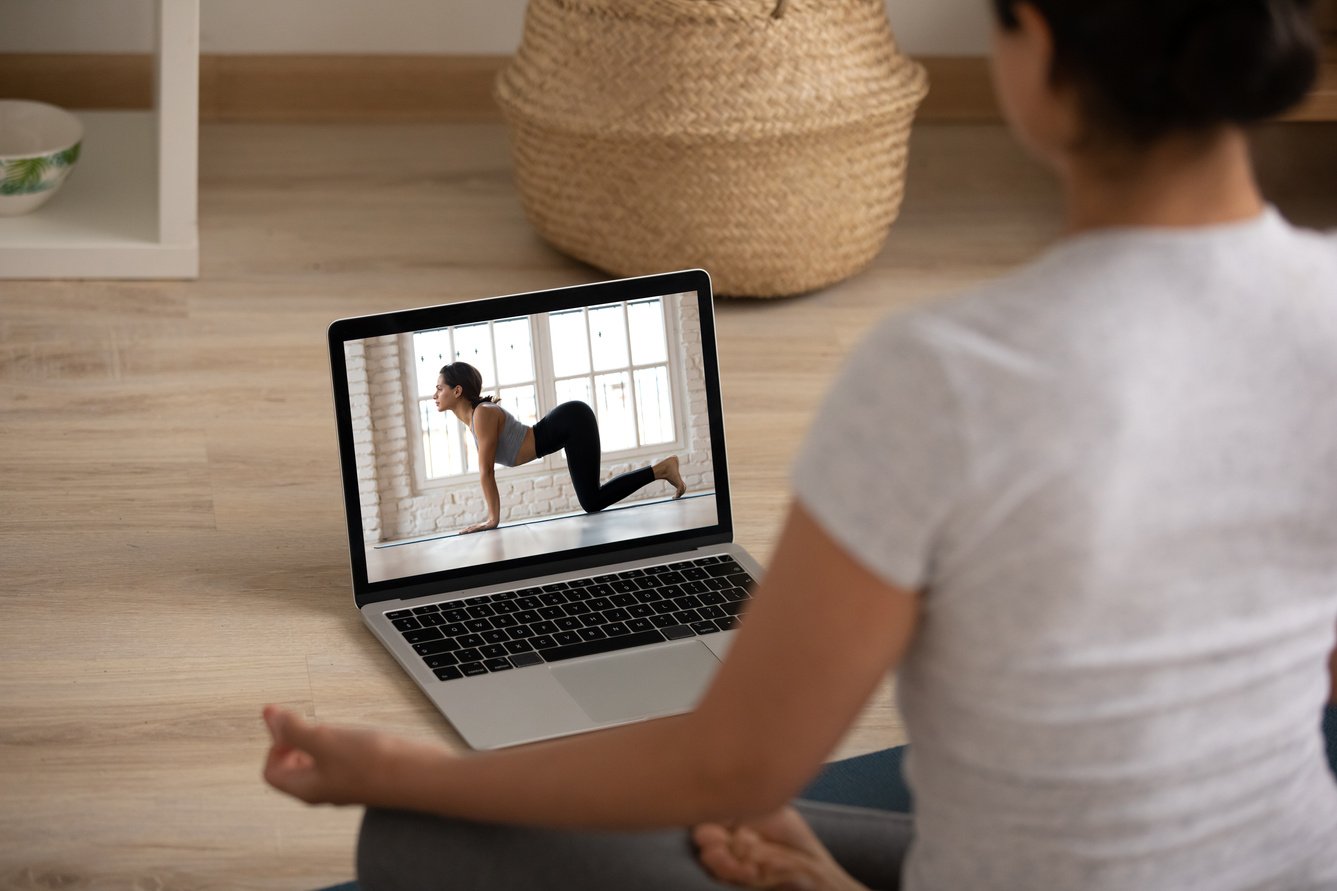 Rear view Indian woman practicing yoga with personal trainer online